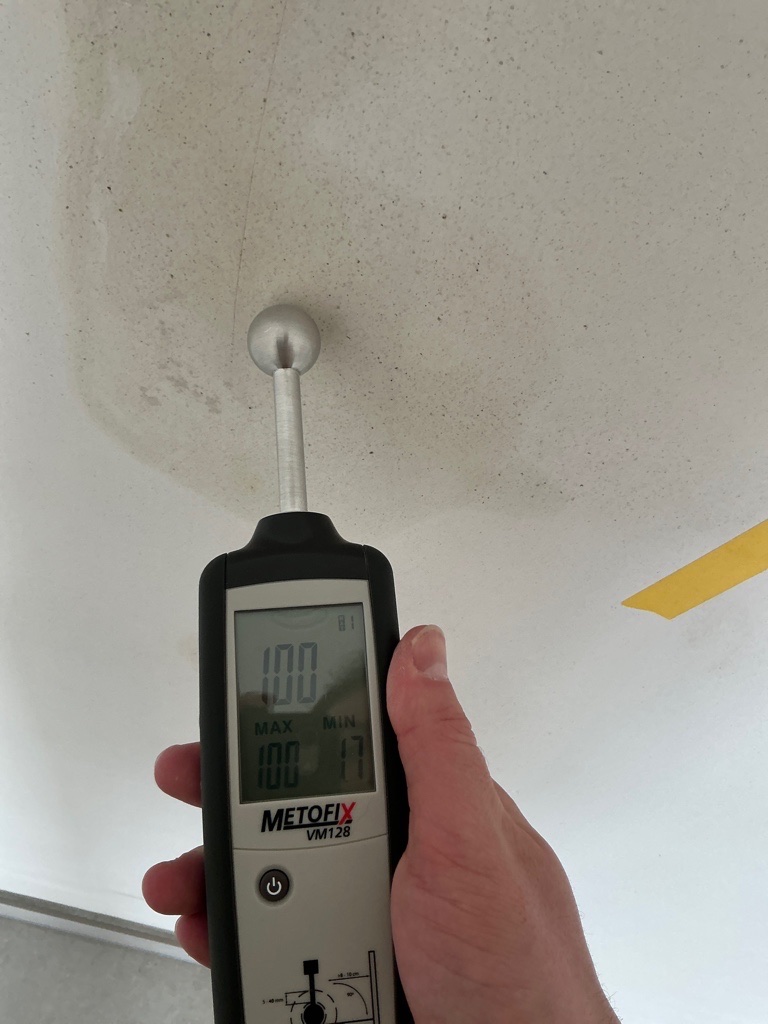 Een vochtmeter wordt tegen een muur gehouden tijdens het onderzoek naar een vochtprobleem