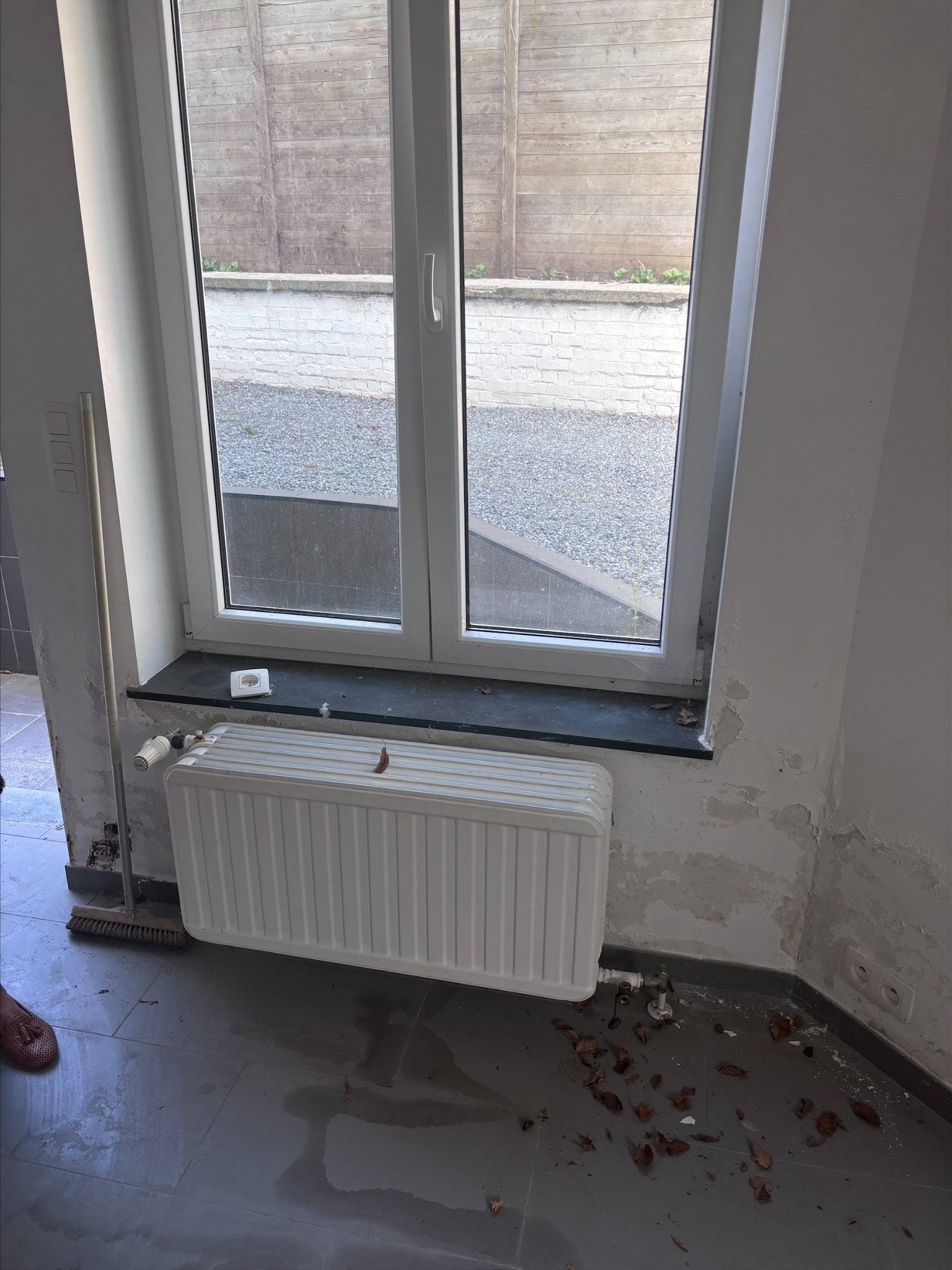 Vochtsporen aan een wand en vloer bij een raam